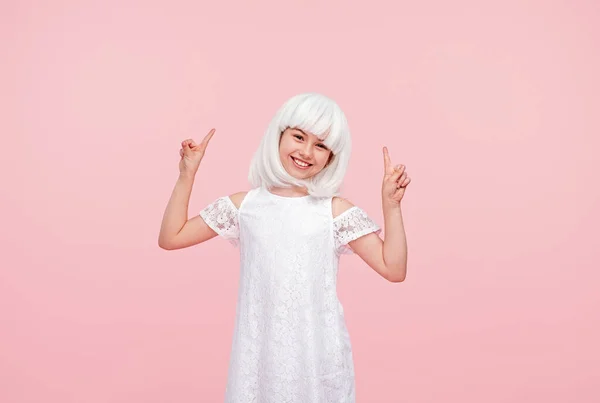 Happy girl in blonde wig pointing fingers up — Stock Photo, Image