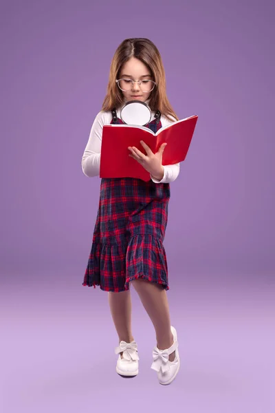 Розумна школярка з книгою для читання збільшувача — стокове фото