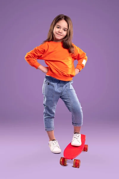Stylish little sporty girl with vivid red skateboard — Stock Photo, Image