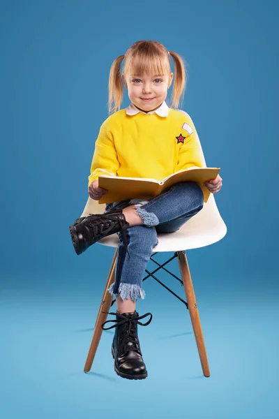 Aranyos óvodás olvasókönyv a székről — Stock Fotó