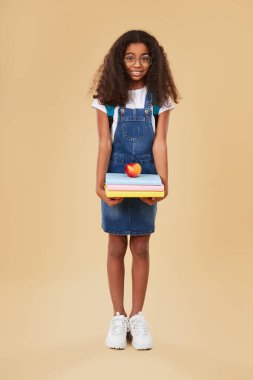 Kitapları ve elması olan mutlu siyah öğrenci.