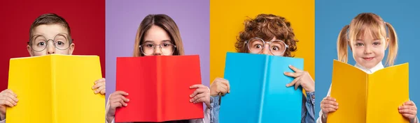 Söta skolflickor och skolpojkar gömmer ansikten med böcker — Stockfoto