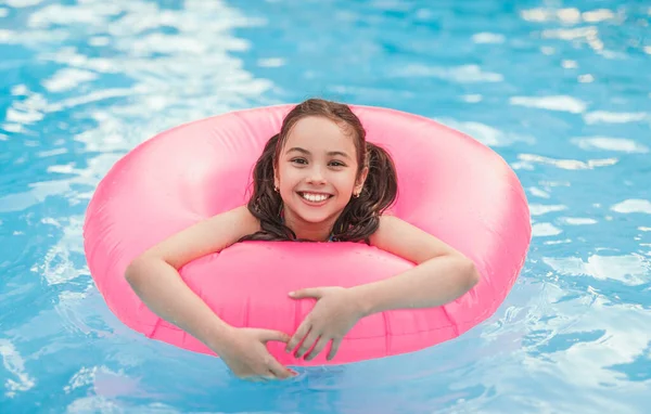 Happy girl with inflatable ring enjoying pool of resort