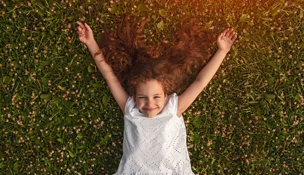 Menina alegre deitado na grama verde — Fotografia de Stock