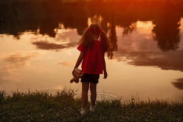 Yalnız küçük kız gölün kıyısında duruyor. — Stok fotoğraf