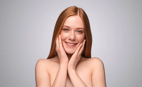 年轻的裸露的女性模特 红头发 触摸着脸 在灰色的背景下微笑着看着相机 — 图库照片