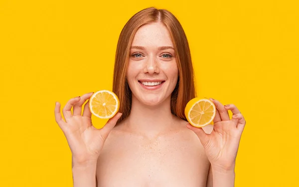 Glückliche rothaarige Frau mit Zitronen blickt in die Kamera — Stockfoto