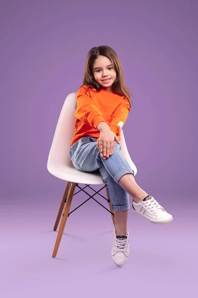 Modern Klein Meisje Casual Oranje Shirt Jeans Zittend Stoel Kijkend — Stockfoto