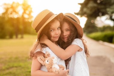 Parkta sarılan sevimli küçük kız kardeşler.