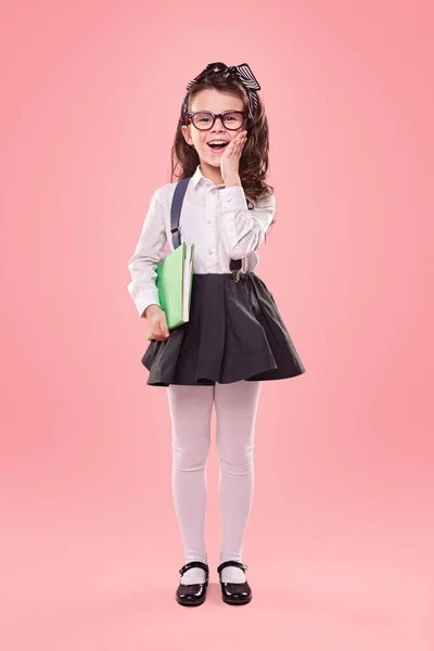 Sorprendida niña de la escuela sobre fondo rosa — Foto de Stock