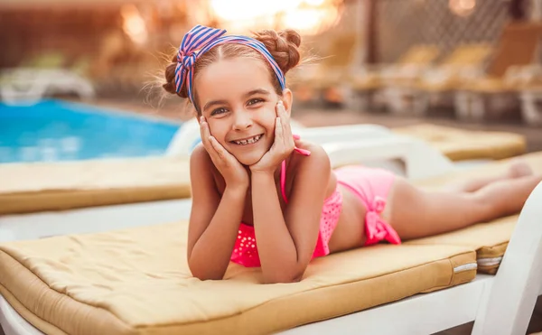 Menina feliz deitado na espreguiçadeira na beira da piscina — Fotografia de Stock