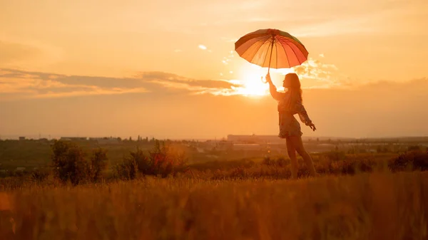 Inspirierendes Weibchen mit Regenschirm gegen den Sonnenuntergang — Stockfoto