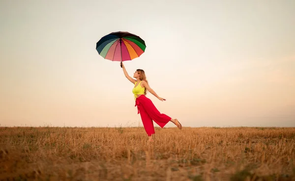 Frau fliegt mit Regenschirm gegen Sonnenuntergang — Stockfoto