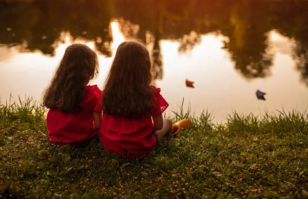 Gêmeos anônimos descansando perto da lagoa — Fotografia de Stock