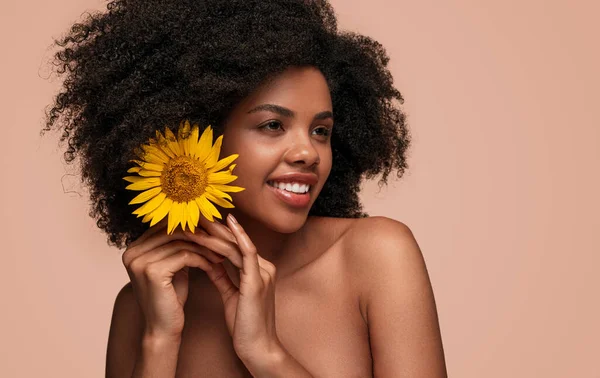 Glad afroamerikansk kvinna sätta blomma i håret — Stockfoto