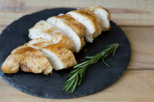 Viande de poulet tranchée servie sur une assiette d'ardoise avec romarin frais — Photo