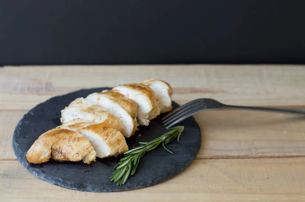 Servir de la viande de poulet tranchée sur une assiette d'ardoise noire — Photo