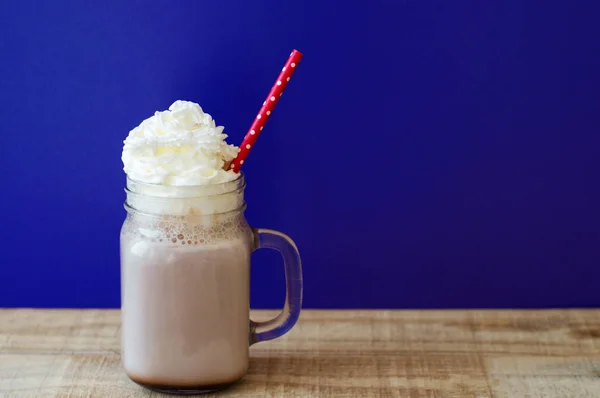 Portion of hot chocolate with white whipped cream in a glass jar