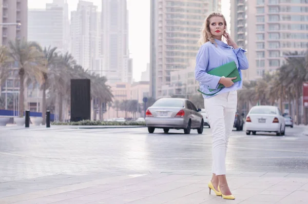 Blond kvinna stående nära trafikerad väg med bilar i Dubai downtown — Stockfoto