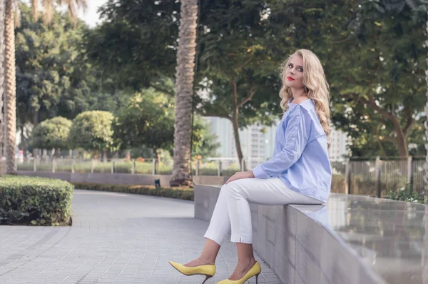 Ung blond kvinna sitter i parken i Dubai downtown — Stockfoto