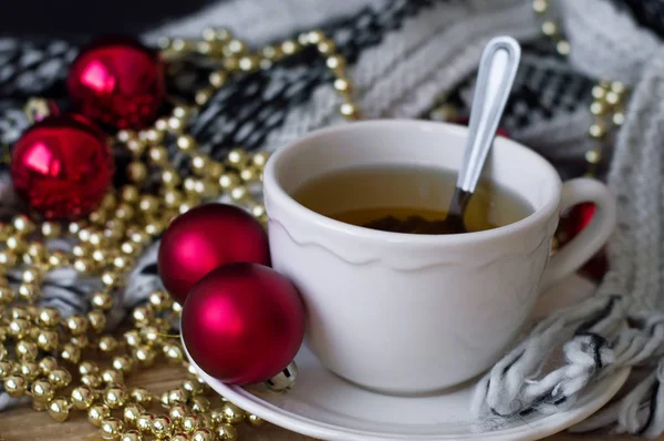 Chá verde em copo de porcelana branca com colher em pé entre a decoração de Natal na mesa de madeira, cobertor de malha como fundo — Fotografia de Stock