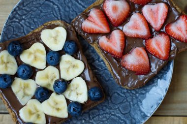 Muz, çilek, yaban mersini, çikolata ile iki meyve sandviç yaymak ve bütün tahıl ekmeği. 