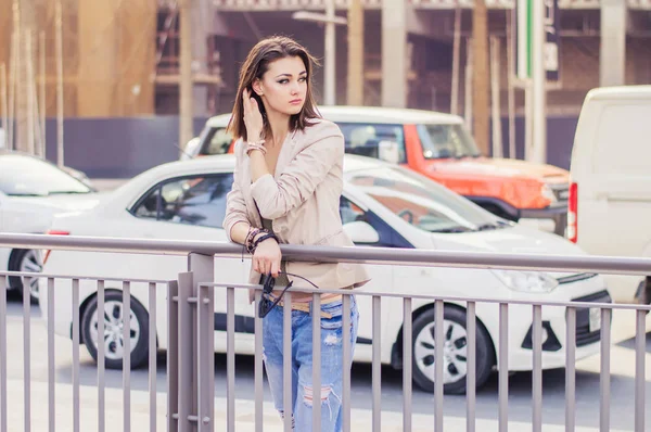 Jovem mulher europeia com bob moderno corte penteado de pé perto da estrada movimentada no centro da cidade. Feminino em jaqueta bege e jeans azuis em pé no centro de Dubai — Fotografia de Stock
