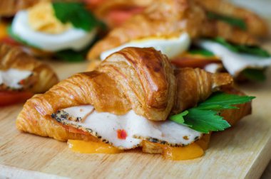 Tereyağı kruvasan tavuk jambon, peynir ve maydanoz ahşap tahta üzerinde. Sıcak kahvaltı sandviç. Sağlıklı meze