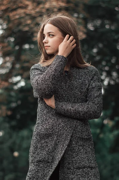 Retrato de bela adolescente em pé no parque em casaco de malha quente. Temporada de outono — Fotografia de Stock