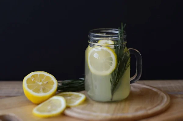 Horizontal photo of cold homemade lemonade with rosemary and lemon slices in a cocktail jar. Detox drink — Stock Photo, Image