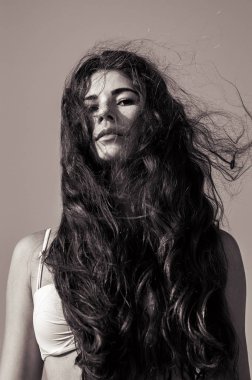 Kendinden emin bir görünüm ile kadın modeli siyah beyaz portre. Ciddi duygu. Güzel uzun kıvırcık saç