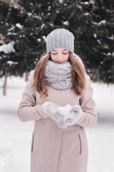 少女抱着心形的雪花球 年轻女孩在针织围巾 手套和帽子站在冬季森林 冬天的心情 冬季时间 — 图库照片