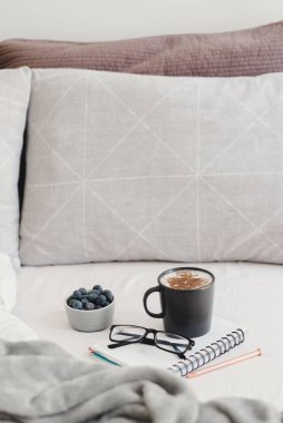 Yatakta kahvaltı: Tarçın tozu ve taze yaban mersinli cappuccino kahvesi evden çalışmak için defter, kalem ve okuma bardaklarıyla servis edilir.