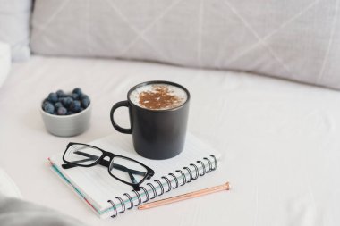 Yataktan çalışmak: bir fincan kapuçino kahve, yabanmersini, okuma gözlüğü, kalem ve not defteri. Çalışırken kahvaltı. Serbest konsept