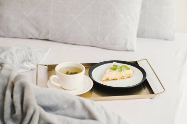 Yatakta kahvaltı: nane çayı ve metal tepside servis edilen bir parça elmalı turta.