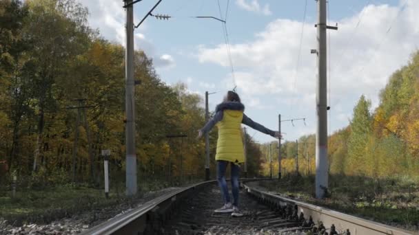 A menina caminha nos trilhos no outono — Vídeo de Stock