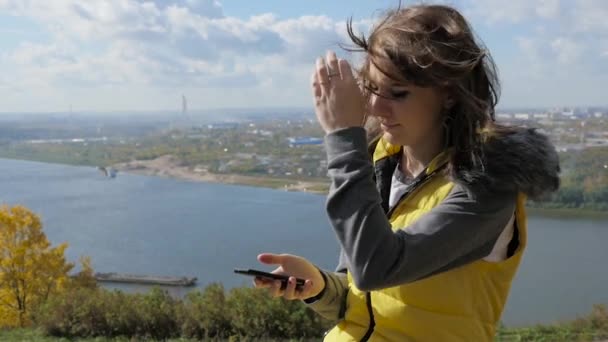 Menina sentada em um banco e olha para o panorama da cidade — Vídeo de Stock