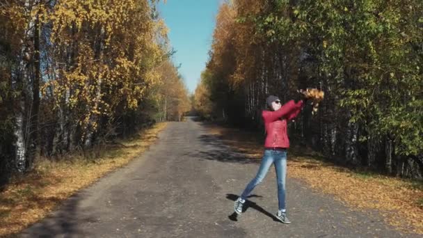 Девушка бросает золотые листья, наслаждаясь осенью — стоковое видео