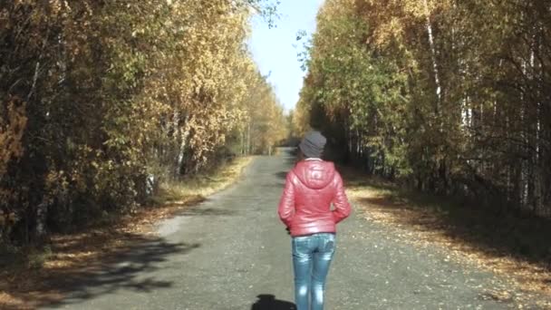 Girl walking on autumn road — Stockvideo