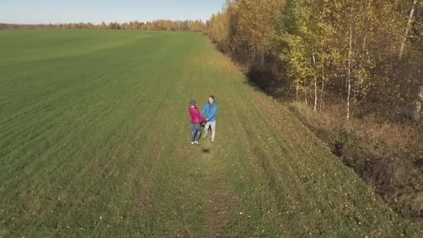 Тень беспилотника, наблюдающего за парнем и девушкой на зеленом поле — стоковое видео