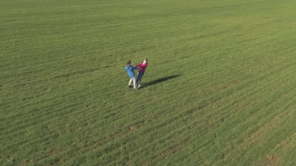The young man and the girl going around on green field — Stockvideo
