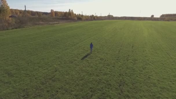 Молодой человек и девушка ходят по зеленому полю — стоковое видео