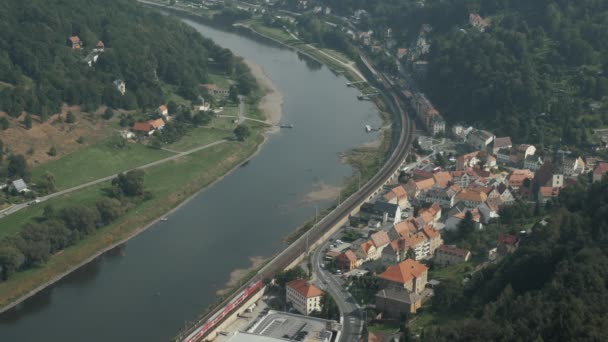 Поезд идет по реке через маленький городок. — стоковое видео
