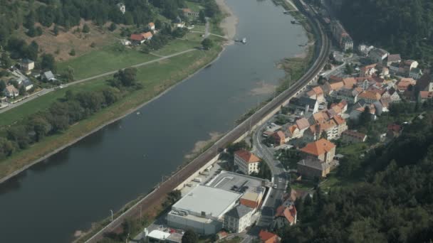 O trem vai ao longo do rio através de uma pequena cidade — Vídeo de Stock