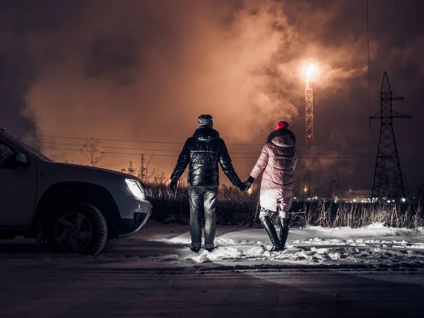 İnsanlar ateşin önünde rafineri bacaları bakmak.