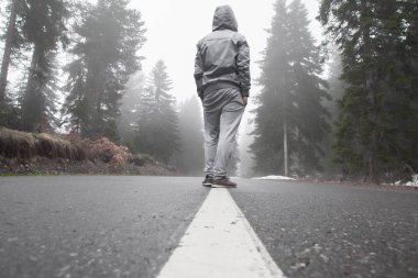 Puslu bir yolda genç bir çocuk duruyor