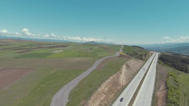 Voitures conduisant sur la route le long des champs verts — Video