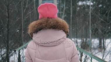 Kız yavaş yavaş kış orman kar yağışı altında size yürür