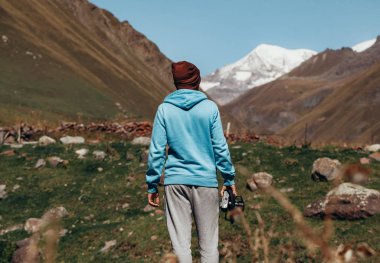 Dağlara bakan mavi ceketli bir fotoğrafçı.