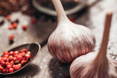 Sarımsaklı kırmızı biber kozalaklı bir dalla ahşap bir masada yatıyor.